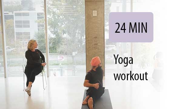 yoga instructor leading seated student in gym