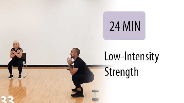 trainer in a squat pose holding a dumbell with both hands